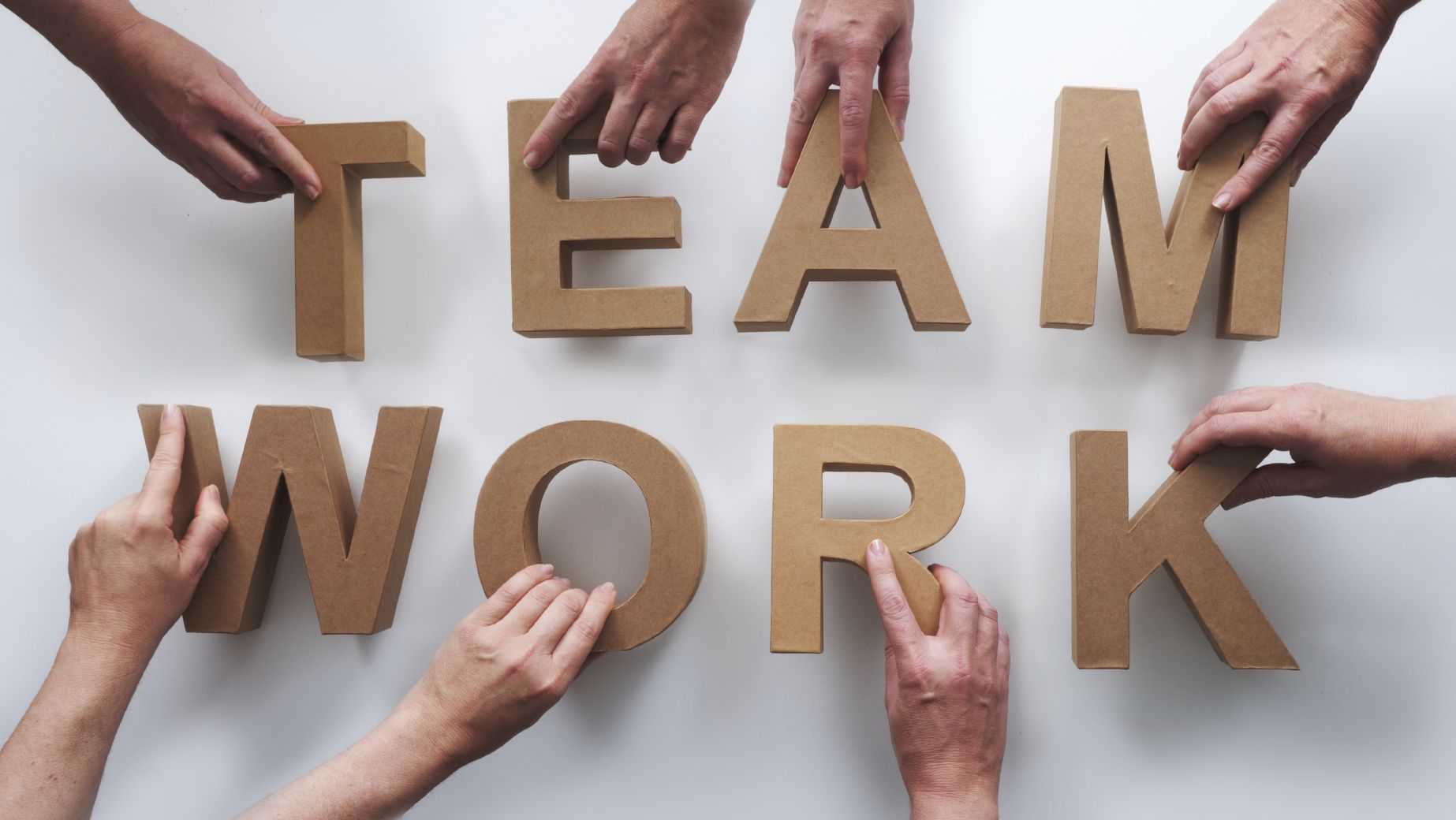a team holding each letter of the words 'team work'